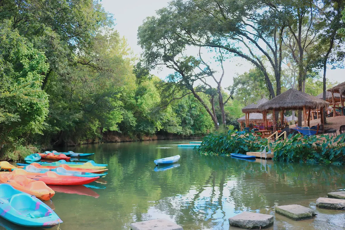 Family relaxing at a creekside cabana with kayaks near San Antonio